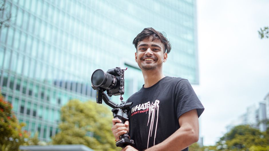 A smiling wedding videographer holding a professional camera on location